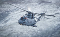Military helicopter flying over snow covered hills